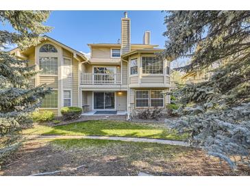 A view of the backyard featuring a grassy lawn, landscaping, and a patio with sliding glass doors at 8208 S High Ct, Centennial, CO 80122