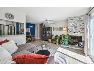 Sunlit living room features a stacked stone fireplace, sleek furnishings, and modern decor at 1225 S Oneida St # 248, Denver, CO 80224