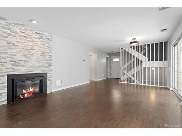 Bright living room with fireplace, wood floors, and staircase leading to the upper level at 2366 S Troy St, Aurora, CO 80014