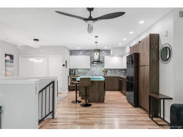 Modern kitchen featuring a large island with seating, stainless steel appliances, and hardwood floors at 3295 Blake St # 102, Denver, CO 80205