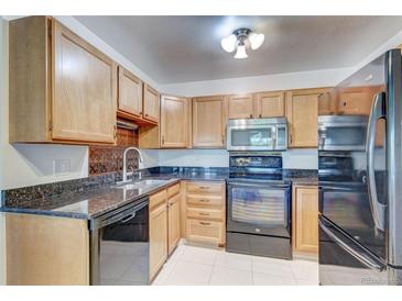 Bright kitchen with wood cabinets, granite counters, and black appliances at 3082 S Wheeling Way # 408, Aurora, CO 80014