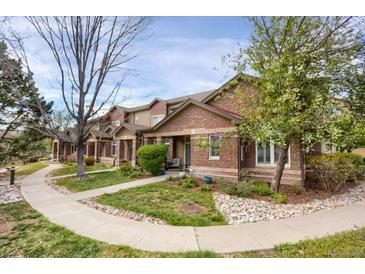 Charming townhome showcasing a manicured front yard, brick facade, and inviting walkway at 6476 Silver Mesa Dr # A, Highlands Ranch, CO 80130