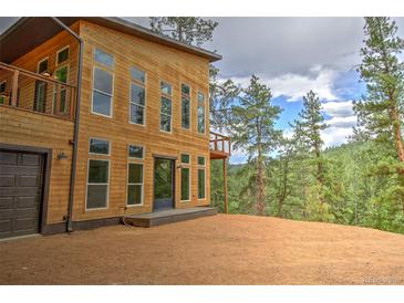 Stunning contemporary home exterior with wood siding, large windows, and a walkout balcony overlooking treed lot at 15175 Rainbow Dr, Sedalia, CO 80135