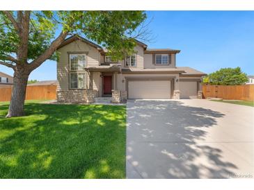 Charming two-story home featuring a well-manicured lawn and a three car garage on a sunny day at 12814 Forest Cir, Thornton, CO 80241