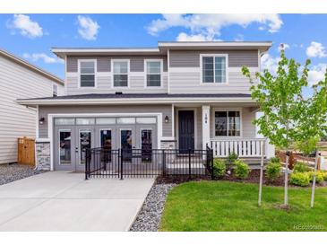Charming two-story home with a landscaped yard, front porch and gray accent colors at 104 Wooten Ave, Brighton, CO 80601