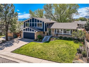 Charming two-story home boasts a lush front yard, blue siding, and inviting entryway at 1977 S Urban St, Lakewood, CO 80228