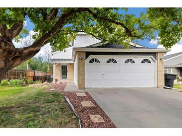 Charming two-story home with a well-maintained lawn, mature tree, and a two-car garage with decorative windows at 11376 Forest Dr, Thornton, CO 80233