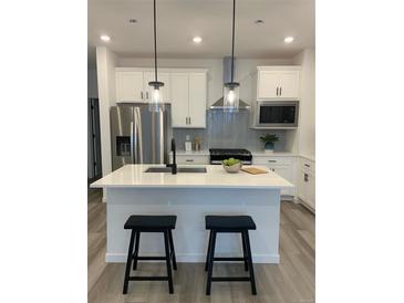 Modern kitchen features a center island, stainless steel appliances, and stylish backsplash at 348 N. Geneva St, Aurora, CO 80010