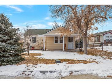 Cute bungalow with covered porch and snow-covered yard at 6900 E 66Th Ave, Commerce City, CO 80022