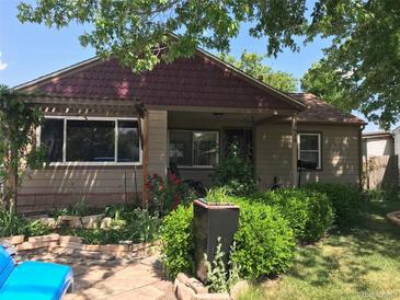 Charming single-story home featuring lush landscaping, a stone pathway, and a welcoming front porch with detailed accents at 5618 Carr St, Arvada, CO 80002