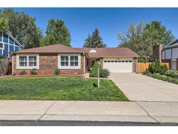 Charming brick home featuring a well-manicured lawn and a two-car garage and lush landscaping at 2093 S Holland St, Lakewood, CO 80227