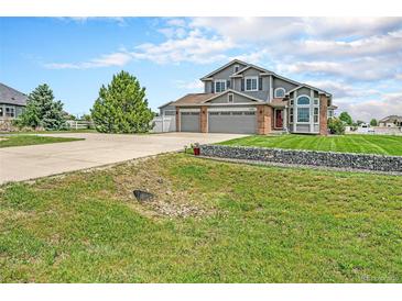 Two-story home featuring a well-maintained lawn, three-car garage, and a large tree in the front yard at 16500 Timber Cove St, Hudson, CO 80642