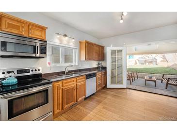 Bright kitchen features stainless steel appliances, wood cabinets and opens to a patio at 3629 Kalamath St, Denver, CO 80211