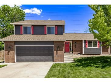 Home with a brick and siding exterior, a two-car garage, and vibrant landscaping, set against a blue sky at 6062 S Newport St, Centennial, CO 80111