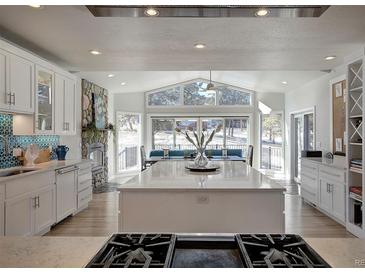 Bright and airy kitchen featuring a large island, stone accents, and scenic views at 5371 Hazel Rd, Evergreen, CO 80439