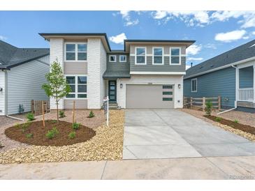 Modern two-story home with a two-car garage, manicured front yard, and a combination of brick and gray siding at 8346 Cokedale Cir, Littleton, CO 80125
