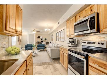 Bright kitchen features stainless steel appliances, light wood cabinets, and flows into the adjacent living area at 1820 Newland Ct # 213, Lakewood, CO 80214