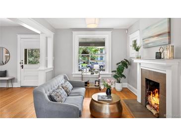 Bright living room features hardwood floors, a cozy fireplace, and large windows at 1545 Steele St, Denver, CO 80206