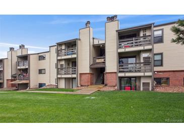 Multi-level condo building with balconies and a well-maintained lawn at 579 Wright St # 204, Lakewood, CO 80228