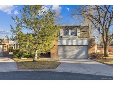 Charming two-story home featuring a brick facade and an attached two-car garage with landscaped yard and mature trees at 21 Birdie Ln, Littleton, CO 80123