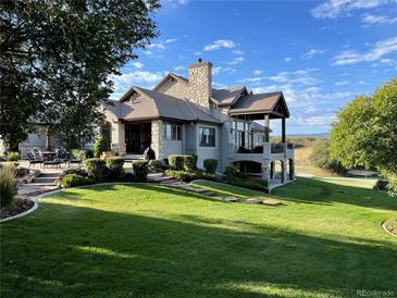 Expansive home showcasing meticulous landscaping, stone accents, a chimney, and a beautiful outdoor patio area at 3080 Big Bear Dr, Sedalia, CO 80135