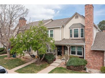 Charming townhome with well-manicured lawn, mature trees and a brick chimney under a partly cloudy sky at 9620 W Chatfield Ave # D, Littleton, CO 80128