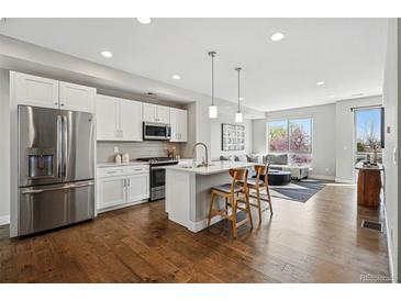 Modern kitchen boasts white cabinets, stainless steel appliances, and a center island, blending style with functionality at 1919 Eaton St, Lakewood, CO 80214