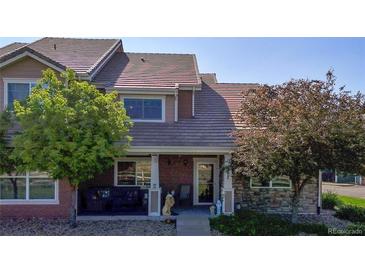 Charming townhome featuring a covered front porch, well-maintained landscaping, and a welcoming entrance at 10449 Paris St # 207, Commerce City, CO 80640