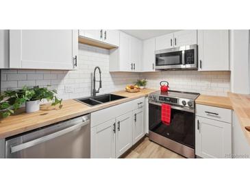 Modern kitchen featuring stainless steel appliances, white cabinets, and butcher block countertops at 9700 E Iliff Ave # A3, Denver, CO 80231