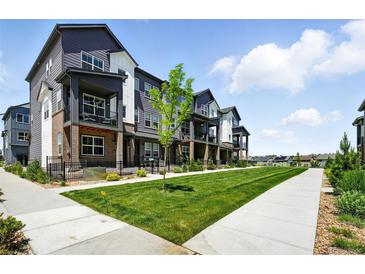 Townhouse exterior featuring gray siding, a well-manicured lawn, and a sidewalk at 6988 Ipswich Ct, Castle Pines, CO 80108