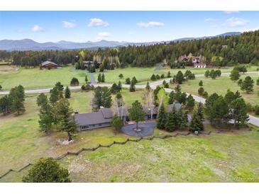 Expansive estate on a verdant lot featuring mature trees, long driveway, and mountain views at 32399 Woodland Dr, Evergreen, CO 80439