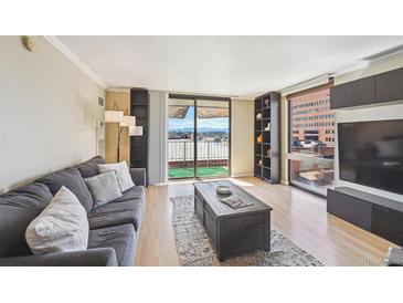 Bright living room with a comfortable gray sofa and a sliding glass door leading to a balcony with mountain views at 1301 Speer Blvd # 403, Denver, CO 80204
