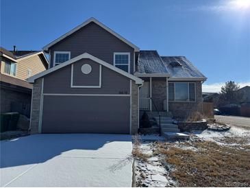 Two-story home showcasing a two-car garage, gray siding and stone accents at 6610 Monaco Way, Brighton, CO 80602