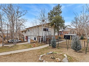 Two story home with fenced yard, driveway, and mature trees on a sunny day at 159 Judson St, Longmont, CO 80501