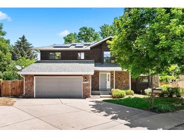 Charming two-story home with a stone and dark wood exterior, a well-maintained lawn, and a two car garage at 4906 S Crystal St, Aurora, CO 80015