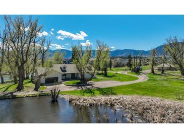 Beautiful home featuring an attached garage, pond, luscious green grass, and mountain views on a bright sunny day at 16440 Old Denver Rd, Monument, CO 80132