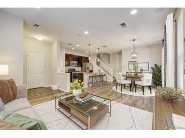 Open-concept living room seamlessly connects the kitchen, dining area, and comfortable seating, perfect for modern living at 3386 Valentia St, Denver, CO 80238