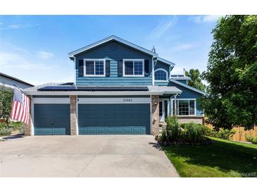 Charming two-story home with a three-car garage, blue siding, manicured lawn, solar panels, and American flag at 21885 Whirlaway Ave, Parker, CO 80138