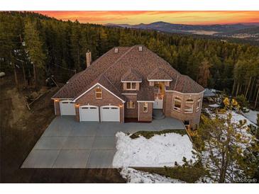 Majestic brick home boasts mountain views, a three-car garage, and a sprawling driveway at 9303 Dauntless Way, Conifer, CO 80433