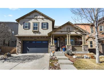 Charming two-story home with stone accents, inviting front porch, and well-manicured landscaping, creating excellent curb appeal at 10828 Valleybrook Cir, Highlands Ranch, CO 80130