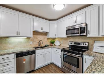 A bright kitchen showcases stainless steel appliances, stone backsplash, and granite countertops at 750 S Alton Way # 4B, Denver, CO 80247