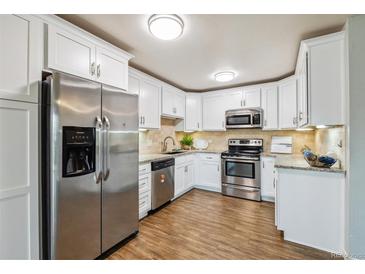 Bright kitchen featuring stainless steel appliances, granite countertops, and white cabinets at 750 S Alton Way # 4B, Denver, CO 80247