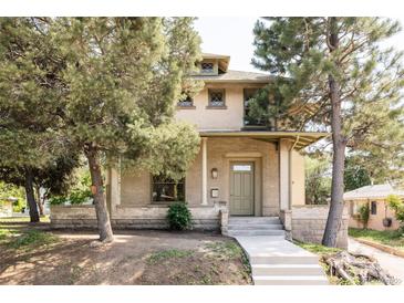 Charming brick two-story home with covered front porch and mature trees providing shade at 3330 Bruce Randolph Ave, Denver, CO 80205