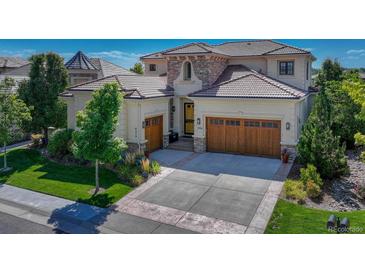 Stunning home exterior with a clay tile roof, three-car garage, and stone accents at 9316 E Harvard Ave, Denver, CO 80231