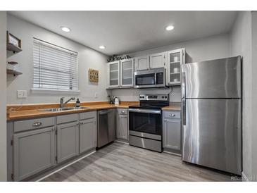 Well-lit kitchen with stainless steel appliances, gray cabinets, wood countertops, and modern flooring at 6705 S Field St # 801, Littleton, CO 80128