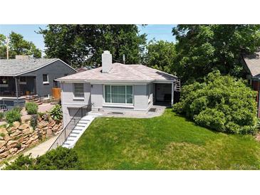 Charming single-story home featuring a stone chimney, lovely brickwork and lush green lawn at 2626 N Steele St, Denver, CO 80205