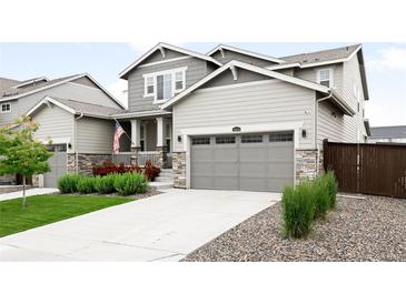 Charming two-story home with gray siding, stone accents, landscaped yard, and a welcoming covered porch at 14454 Grape Way, Brighton, CO 80602