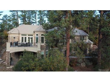 Beautiful home with a stone facade, a balcony and a lush green landscape with mature trees at 226 Hidden Valley Ln, Castle Rock, CO 80108