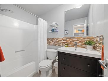 Bright bathroom features a shower-tub combo, mosaic backsplash, vanity, and modern fixtures at 9240 W 49Th Ave # 317, Wheat Ridge, CO 80033