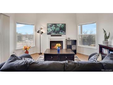 Bright living room with hardwood floors, a cozy fireplace, and plenty of natural light at 2428 W 82Nd Pl # 3A, Westminster, CO 80031